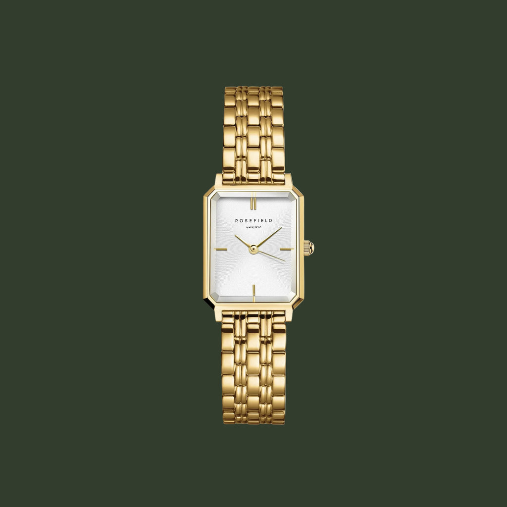 Gold watch with a white face on a light gray background