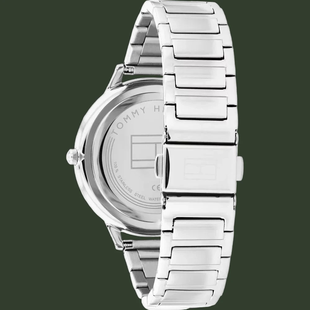 Tommy Hilfiger stainless steel watch shown from the back, featuring a silver metal link bracelet and a clear crystal case back with brand lettering.