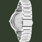 Tommy Hilfiger stainless steel watch shown from the back, featuring a silver metal link bracelet and a clear crystal case back with brand lettering.
