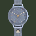 A Tommy Hilfiger men's analog watch with a silver-tone stainless steel case and mesh strap, featuring a textured gray dial with gold-tone hands and indices, and the brand's signature flag logo on the dial.