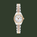 A women's two-tone stainless steel and rose gold watch by Rains, featuring a white dial with crystal hour markers and a date window at the 3 o'clock position.