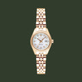 A women's wristwatch with a rose gold metal case and link bracelet, featuring a white dial with crystal hour markers and a date window at the 3 o'clock position.