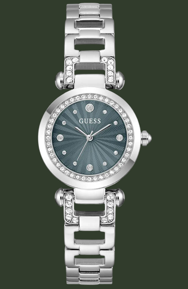 A women's GUESS watch with a silver-tone metal link bracelet, a round bezel set with clear crystals, and a textured dark blue-green dial.