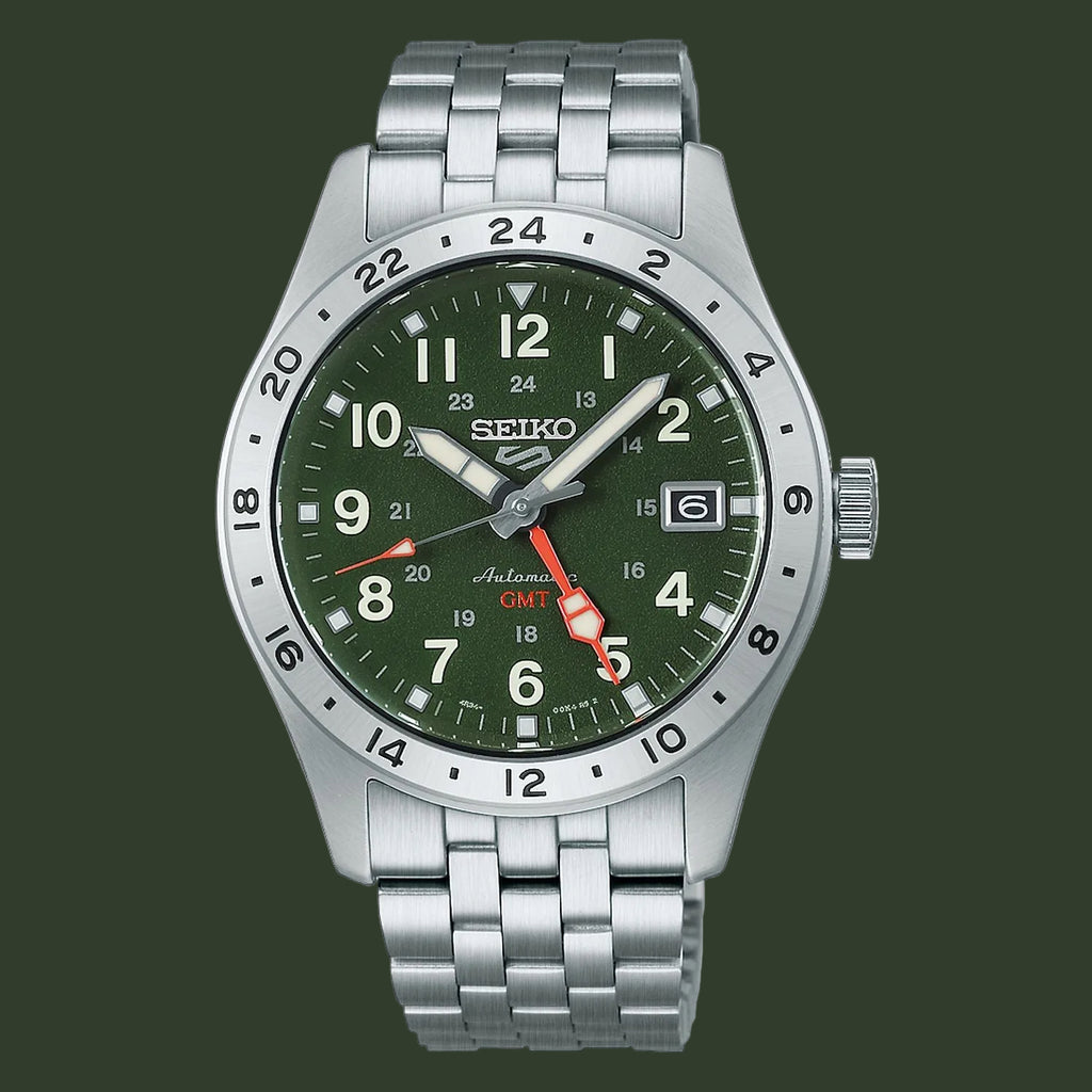 A Seiko Automatic GMT watch with a silver stainless steel link bracelet, a green dial, and a silver rotating bezel, shown on a plain white background.