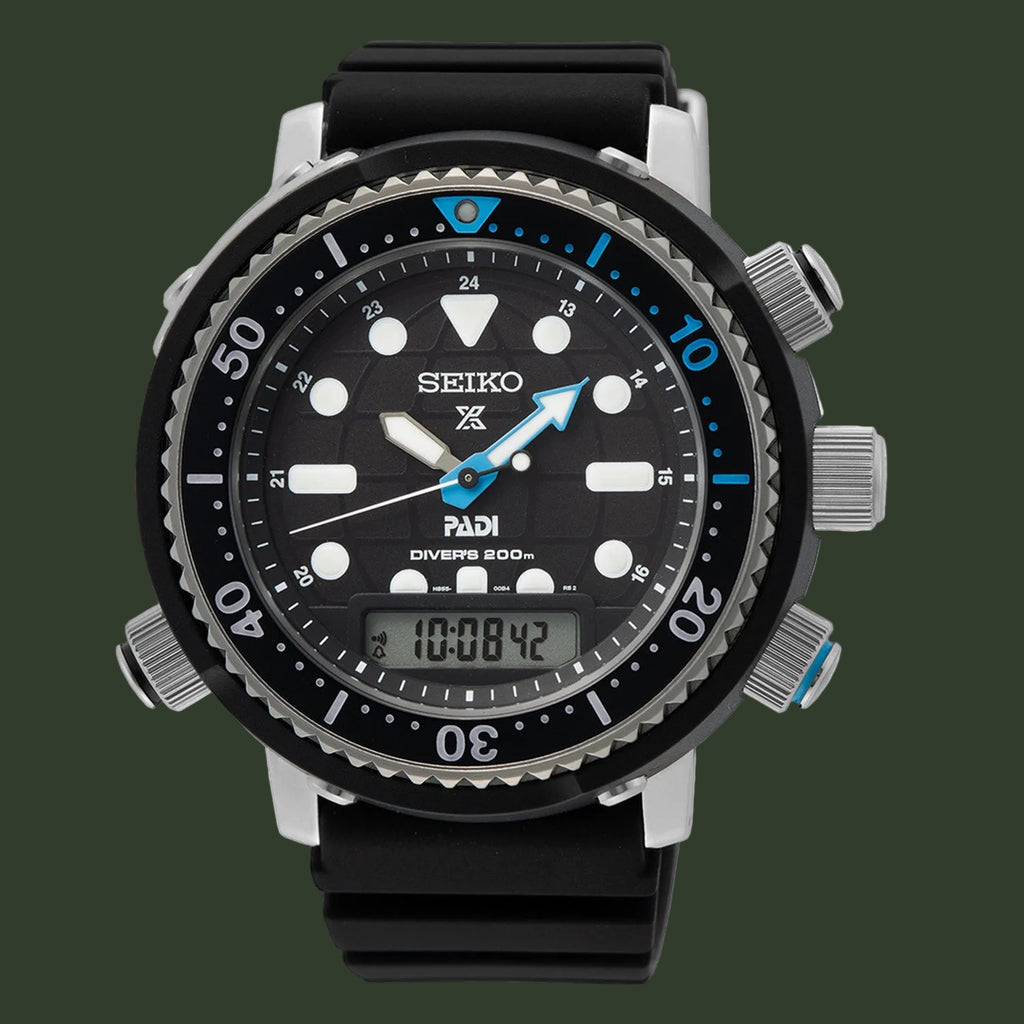 A Seiko x Padi Diverse 300 dive watch with a black dial, black bezel, and black rubber strap, featuring silver-tone case details and blue accents on the hands and bezel.