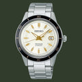 A Seiko Presage Automatic watch with a silver stainless steel link bracelet, a cream-colored dial with gold-tone hands and markers, and a black rotating bezel.