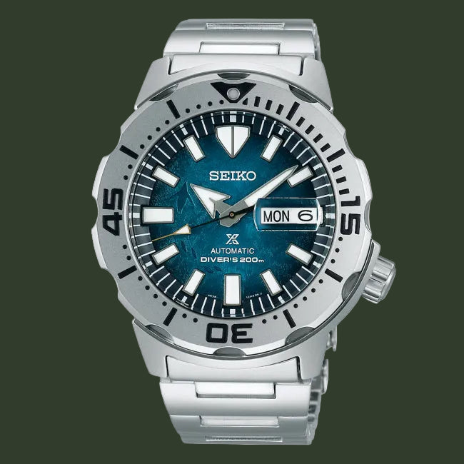 A Seiko automatic dive watch with a silver stainless steel case and bracelet, featuring a textured blue dial, black bezel markings, and a day-date window.