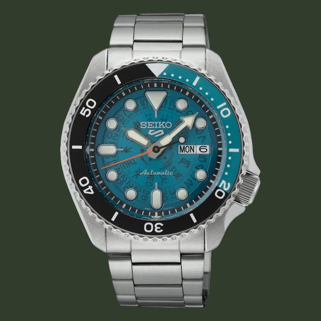 A Seiko stainless steel automatic watch with a blue dial, black bezel, and silver link bracelet, shown against a plain white background.