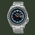 A Seiko automatic watch with a stainless steel link bracelet, featuring a black dial, a black and white checkered bezel, and light blue hour markers.