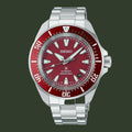 A Seiko automatic dive watch with a silver stainless steel bracelet and case, featuring a red dial and a red rotating bezel with white markings.