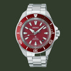 A Seiko automatic dive watch with a silver stainless steel bracelet and case, featuring a red dial and a red rotating bezel with white markings.