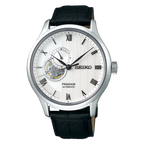 A Seiko Presage Automatic watch with a silver-tone stainless steel case, a white textured dial featuring a skeletonized window showing the inner movement, and a black leather strap.