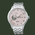 Seiko watch with pink face and silver metal strap on white background
