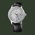 A Seiko wristwatch with a silver stainless steel case, a silver sunburst dial with blue Arabic numerals, and a black leather strap with blue stitching, shown against a plain white background.