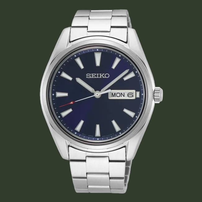 A Seiko stainless steel wristwatch with a dark blue dial, silver-tone metal case and bracelet, silver-tone hour markers, and a day/date window at 3 o'clock.