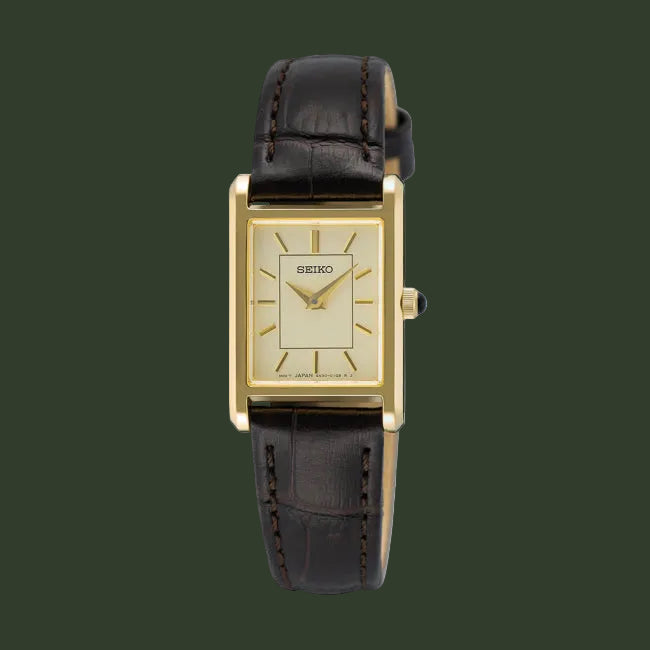A Seiko women's watch featuring a gold-tone rectangular case, a cream-colored dial with gold hands and indices, and a dark brown leather strap with visible stitching.