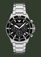 An Emporio Armani 100m/200m Solar chronograph watch with a black dial, black bezel, and a silver stainless steel link bracelet, shown against a plain white background.