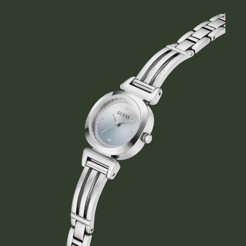 A silver-tone stainless steel women's watch by Guess, featuring a round silver dial with a light blue iridescent gradient center, crystal gemstone hour markers, and a matching multi-link bracelet, shown on a plain white background.