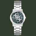 A Guess women's analog watch with a silver-tone stainless steel link bracelet, a round silver-tone case, and a dark green dial featuring the Guess logo and crystal accents.