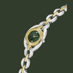 A two-tone stainless steel and yellow gold Guess watch with a dark green dial and crystal-encrusted bezel, shown on a white background.