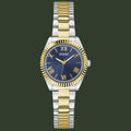 A Guess women's two-tone metal watch with a blue dial, gold-tone Roman numerals, and a link bracelet alternating between gold and silver-tone stainless steel.