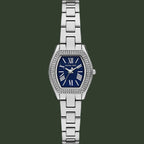 Michael Kors women's analog watch with a silver-tone metal link bracelet, a bezel set with small clear stones, and a deep blue dial with white Roman numerals.