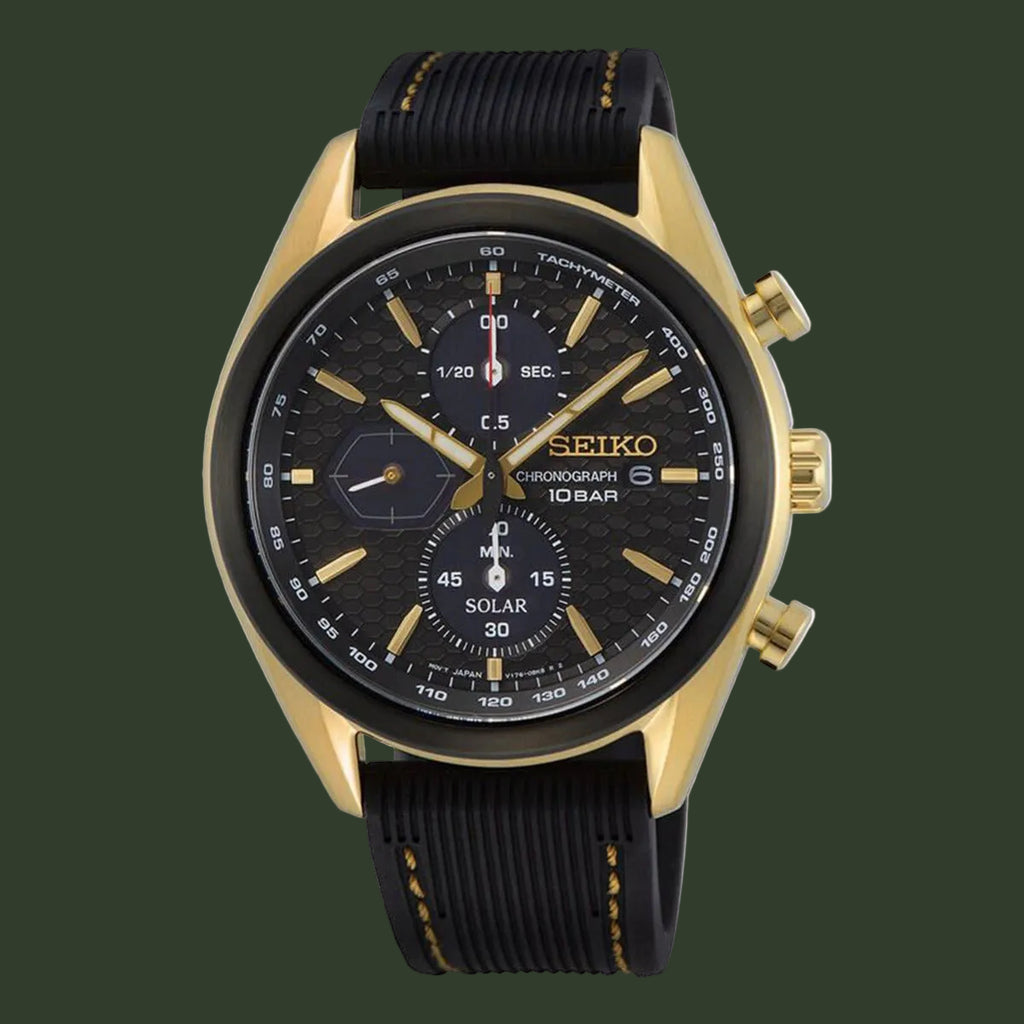 A Seiko chronograph watch with a gold-tone case, black textured dial, and black rubber strap with gold stitching, shown against a plain white background.
