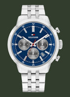 A Tommy Hilfiger men's chronograph watch with a silver stainless steel case and link bracelet, featuring a blue dial with silver subdials and markers.