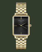 Gold watch with black face on a white background